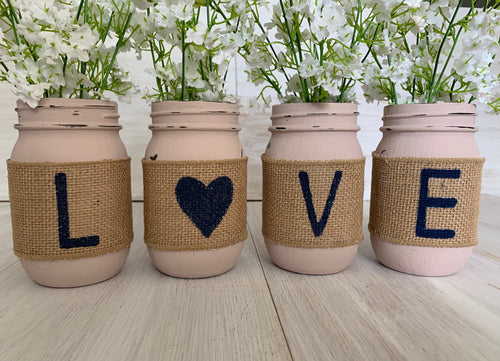 Four pink mason jars with the letters 