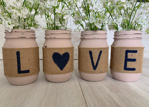 Four pink mason jars with the letters "L O V E" spelled out, one letter per jar