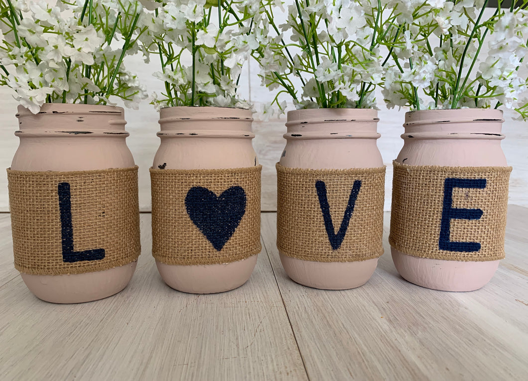 Four pink mason jars with the letters 